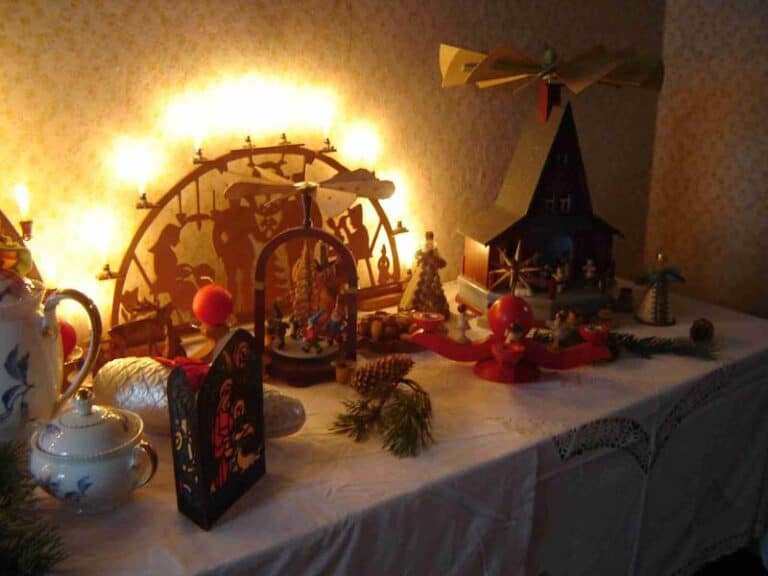 Auf dem Bild ist ein dekorierter Tisch zu sehen, der mit weihnachtlicher Holzdekoration und Porzellangefäßen geschmückt ist