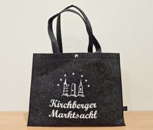 Auf dem Bild ist das Kirchberger Marktsackl zu sehen, eine graue Tasche mit weißem Aufdruck und Logo