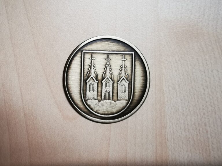 Auf dem Bild ist ein Abzeichen aus Messing zu sehen. Es zeigt das Wappen der Stadt Kirchberg