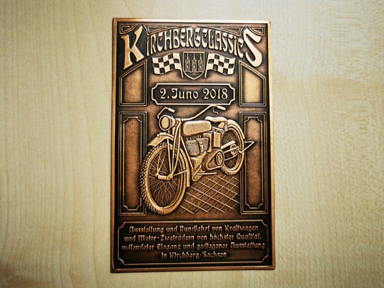Auf dem Bild ist eine kupferfarbene Plakette „Kirchberg Classics“ 2018 mit einem Oldtimer-Motorrad und nostalgischen Schriftzügen zur Ausstellung und Rundfahrt zu sehen