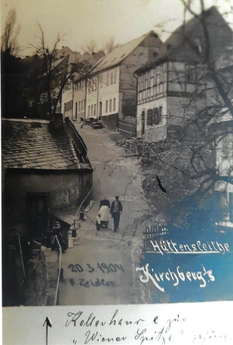 Schwarz-Weiß-Foto einer Straße mit mehreren Wohnhäusern, auf der Personen laufen