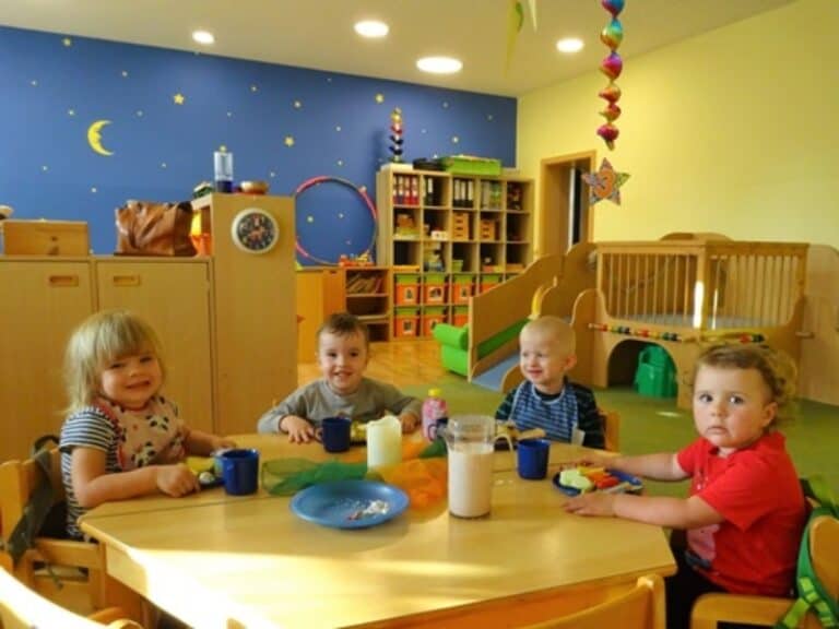 Auf dem Bild sind vier Kinder zu sehen, die zusammen an einem Tisch sitzen und essen