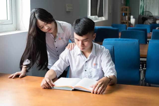 Auf dem Bild ist eine Frau zu sehen, die einen Jungen beim Lernen betreut