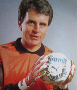Ein Bild von Jürgen Croy im orangenen Trikot und mit einem Fußball in den Händen